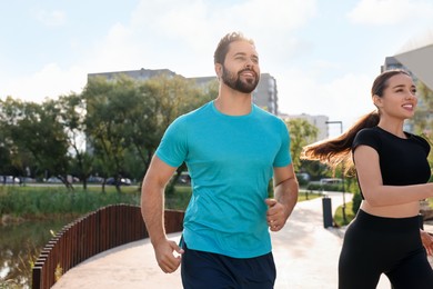 Photo of Healthy lifestyle. Happy couple running outdoors on sunny day