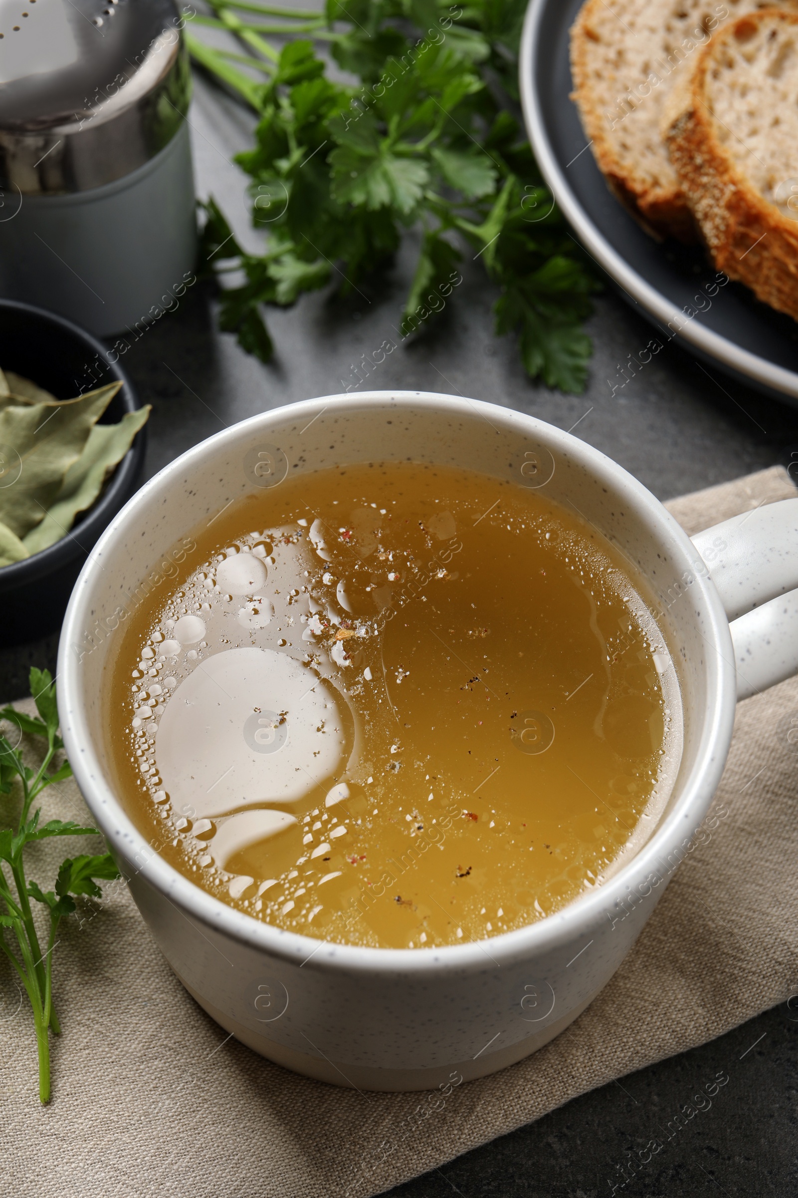 Photo of Hot delicious bouillon in cup on grey table, above view