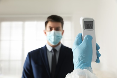 Doctor measuring man's temperature in office closeup. Prevent spreading of Covid-19