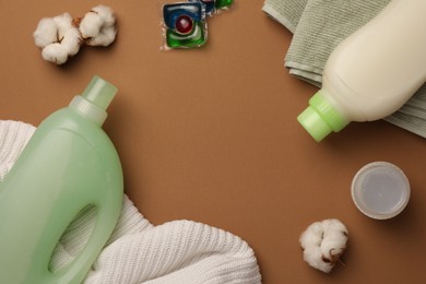 Photo of Flat lay composition with bottle of fabric softener and laundry detergent pods on brown background, space for text