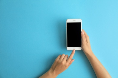 Photo of Woman holding modern phone on blue background, top view. Space for text