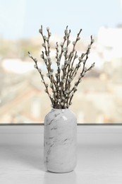 Beautiful pussy willow branches in vase on window sill indoors