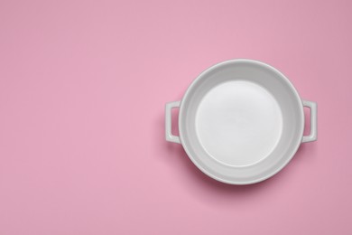 White empty pot on pink background, top view. Space for text