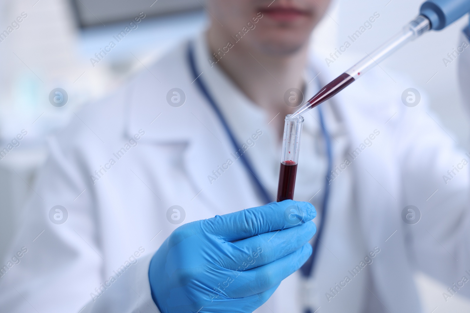 Photo of Scientist dripping sample into test tube in laboratory, closeup