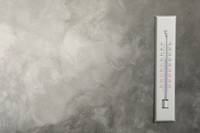 Photo of Weather thermometer on grey wall. Space for text