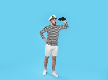 Shocked sailor with binoculars on light blue background