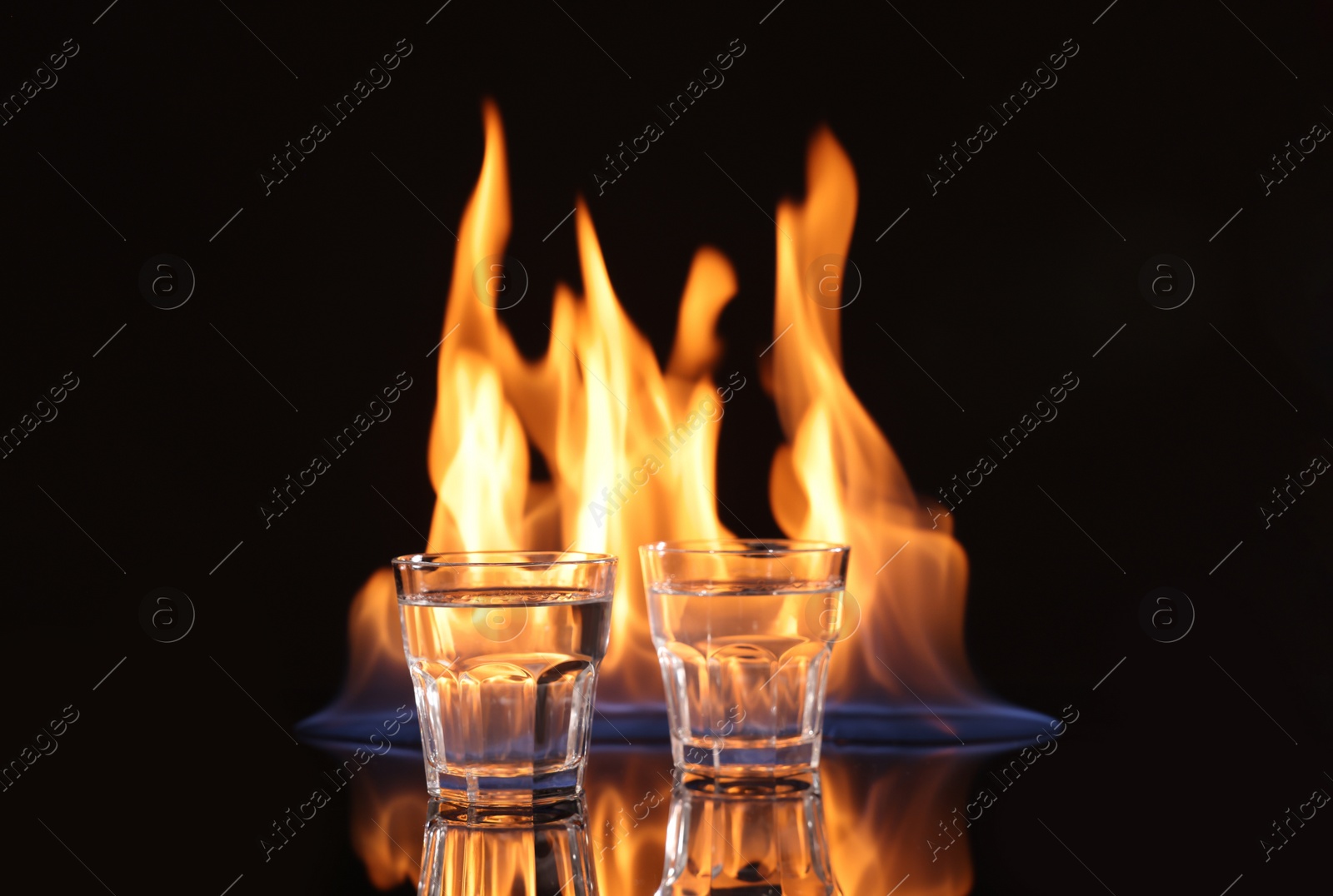 Photo of Vodka in glasses and flame on black background