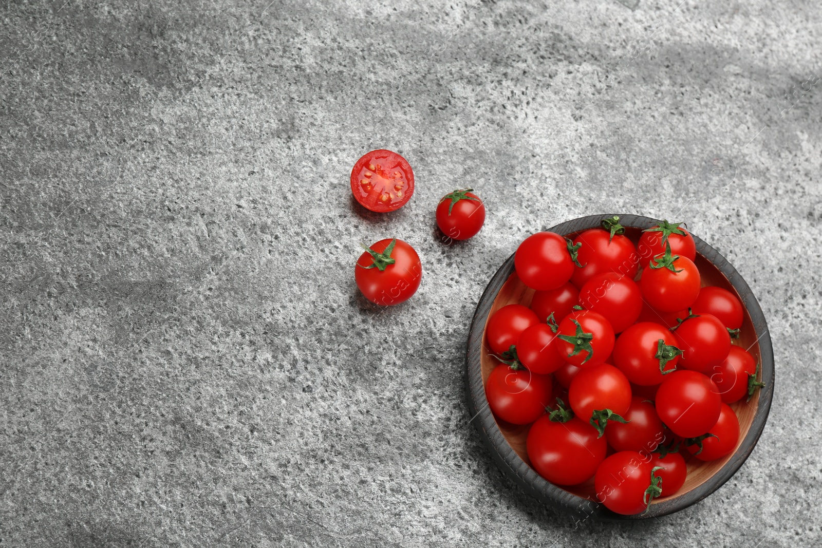 Photo of Fresh cherry tomatoes and wooden bowl on grey table, flat lay. Space for text