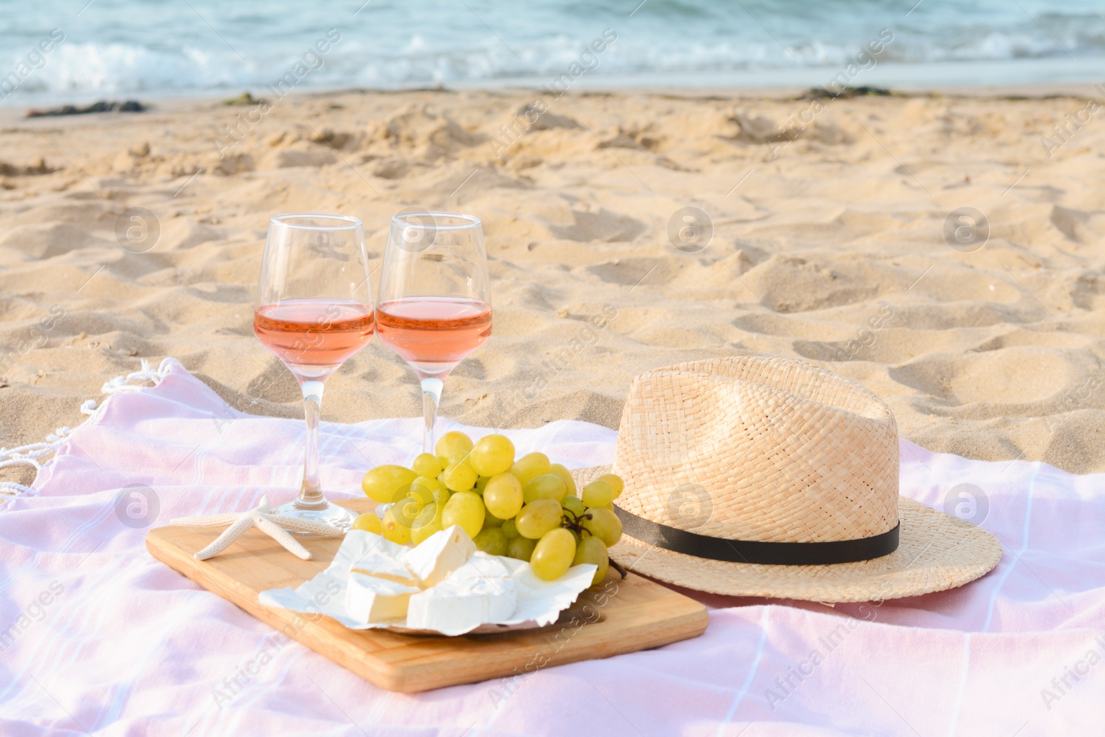 Photo of Glasses with rose wine and snacks for beach picnic on sandy seashore