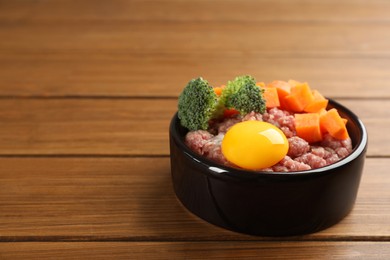 Natural pet food in feeding bowl on wooden table, closeup. Space for text