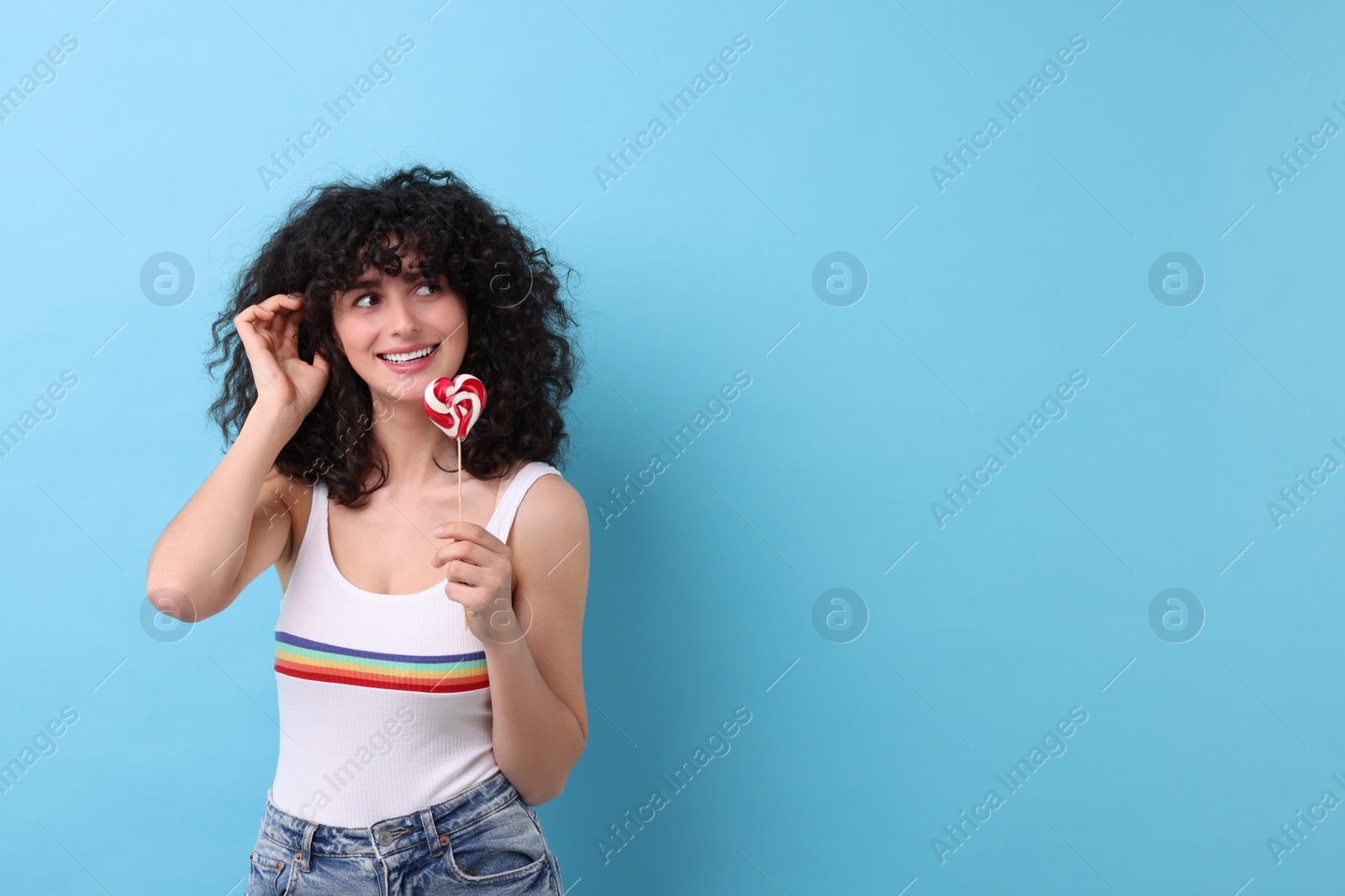 Photo of Beautiful woman with lollipop on light blue background, space for text