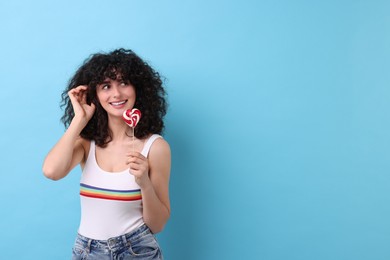 Beautiful woman with lollipop on light blue background, space for text