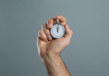 Photo of Man holding vintage timer on grey background, closeup