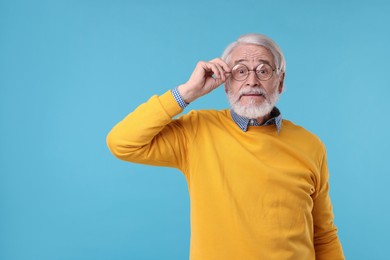 Photo of Portrait of stylish grandpa with glasses on light blue background