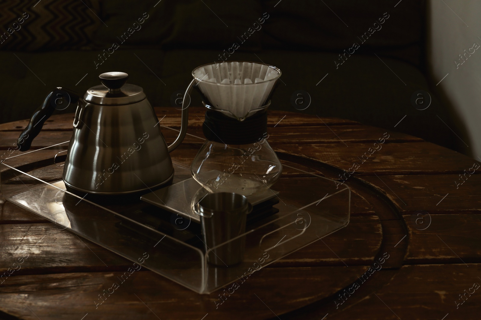 Photo of Cup with coffee, wave dripper and kettle on wooden table in cafe