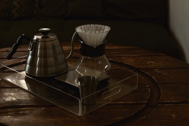 Cup with coffee, wave dripper and kettle on wooden table in cafe