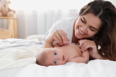 Happy young mother with her cute baby on bed at home