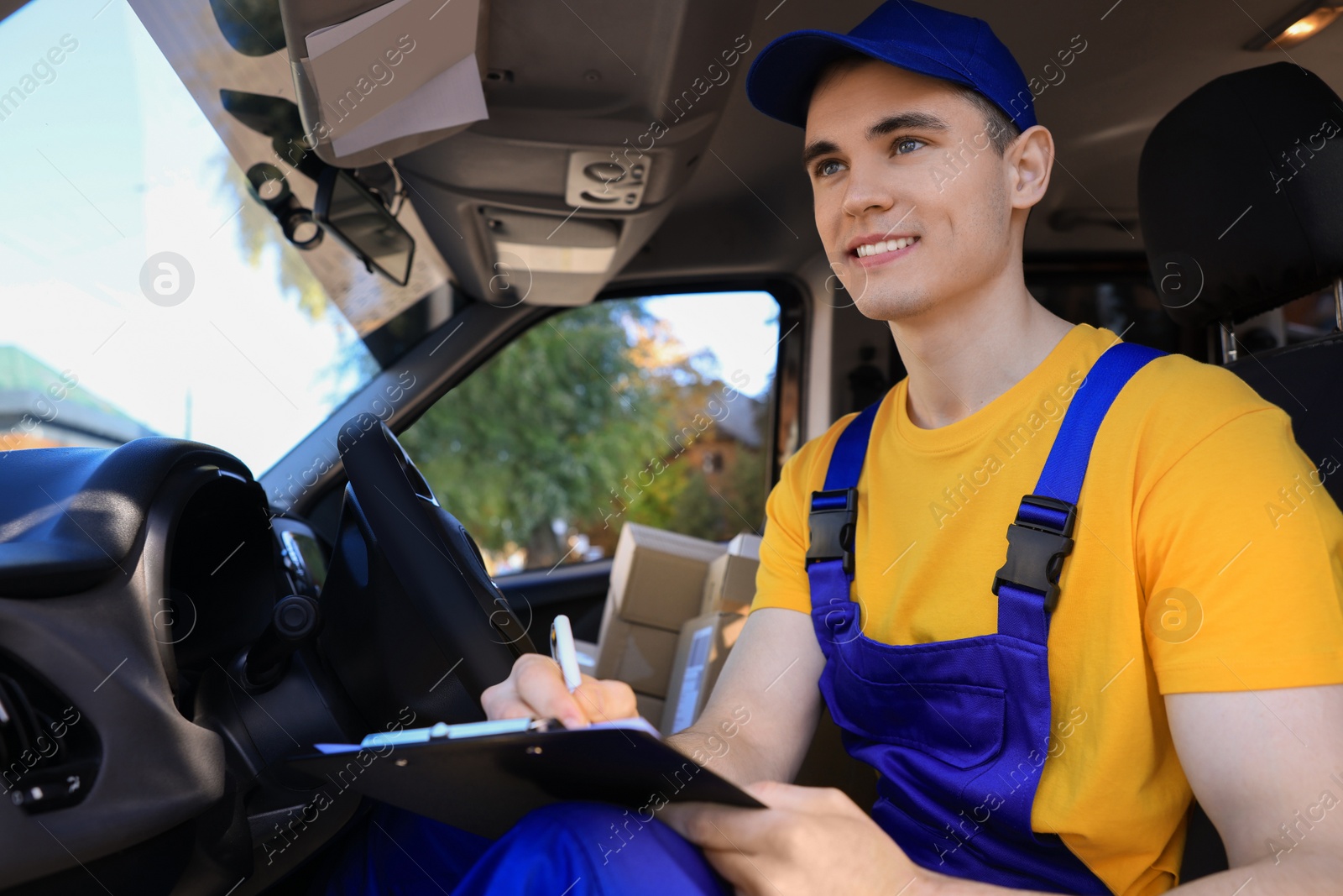 Photo of Courier with clipboard checking packages in car