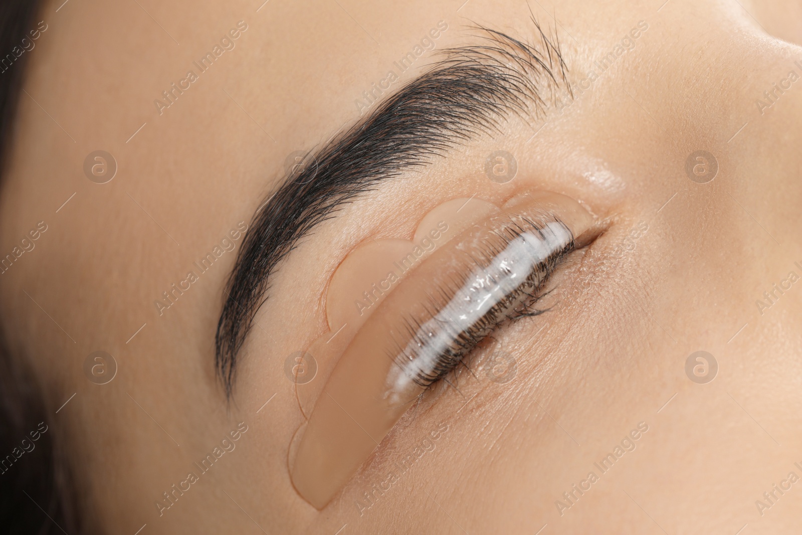 Photo of Young woman undergoing eyelash lamination, closeup. Professional service