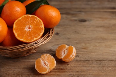 Photo of Delicious tangerines with leaves on wooden table. Space for text