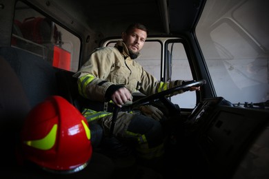Photo of Firefighter in uniform driving modern fire truck