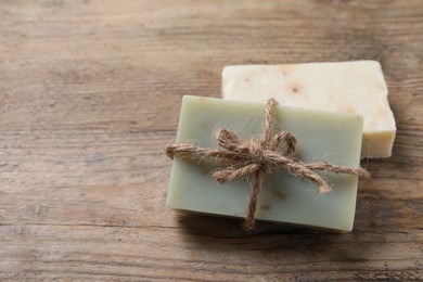 Photo of Soap bars on wooden table, closeup. Space for text