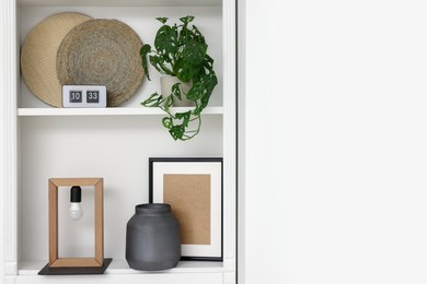 Shelves with different decor near white wall, space for text. Interior design