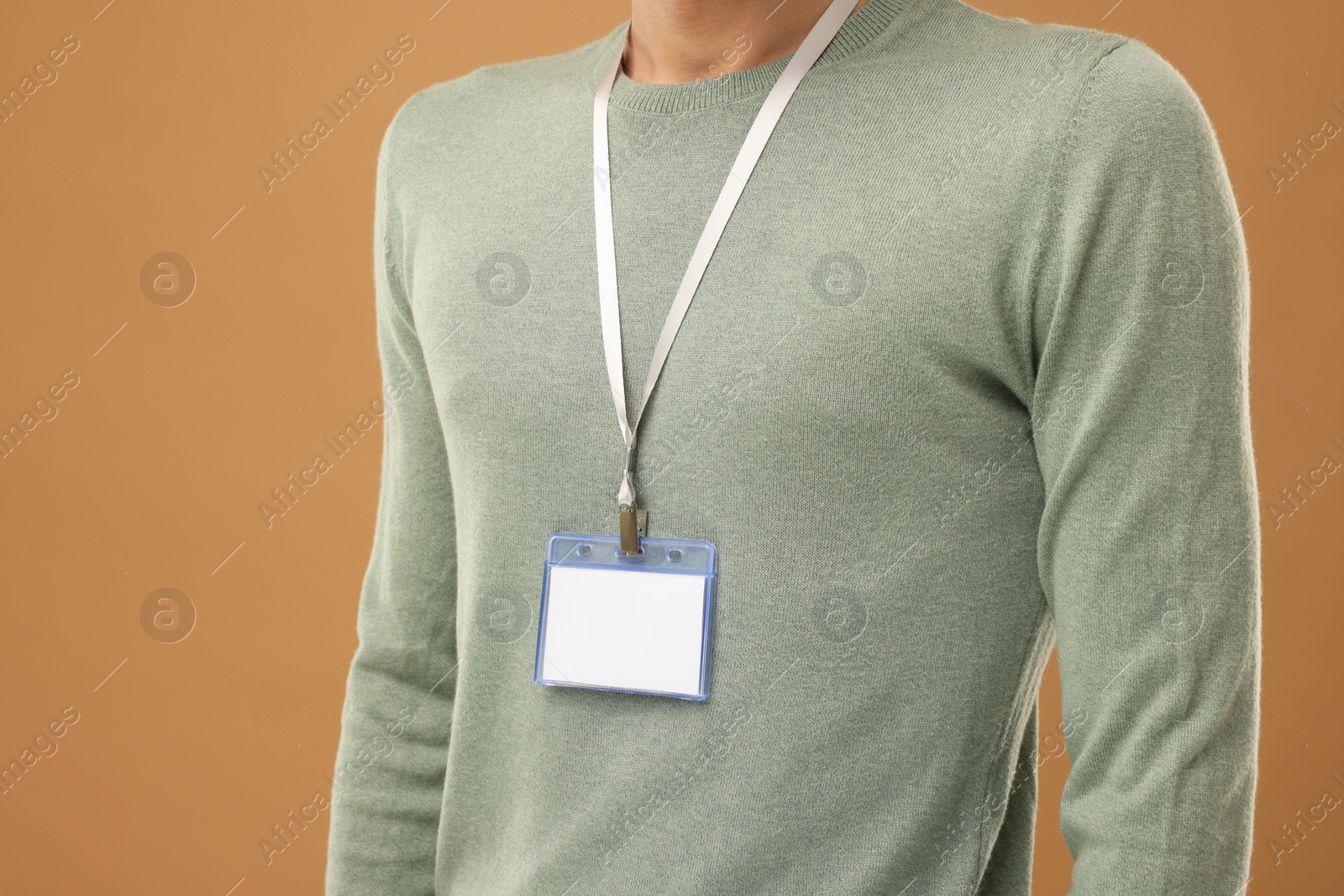 Photo of Man with blank badge on light brown background, closeup