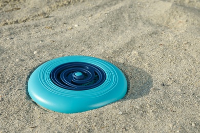 Photo of Blue plastic frisbee disc on sandy beach