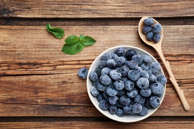 Photo of Tasty frozen blueberries on wooden table, flat lay. Space for text