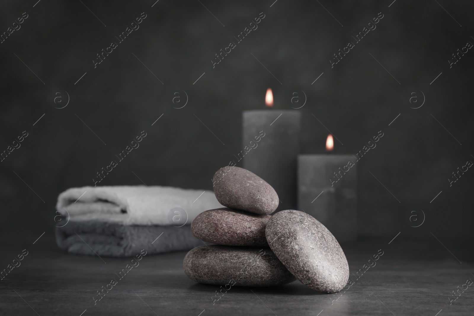 Photo of Spa stones with candles and towel on grey table