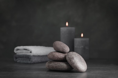 Spa stones with candles and towel on grey table