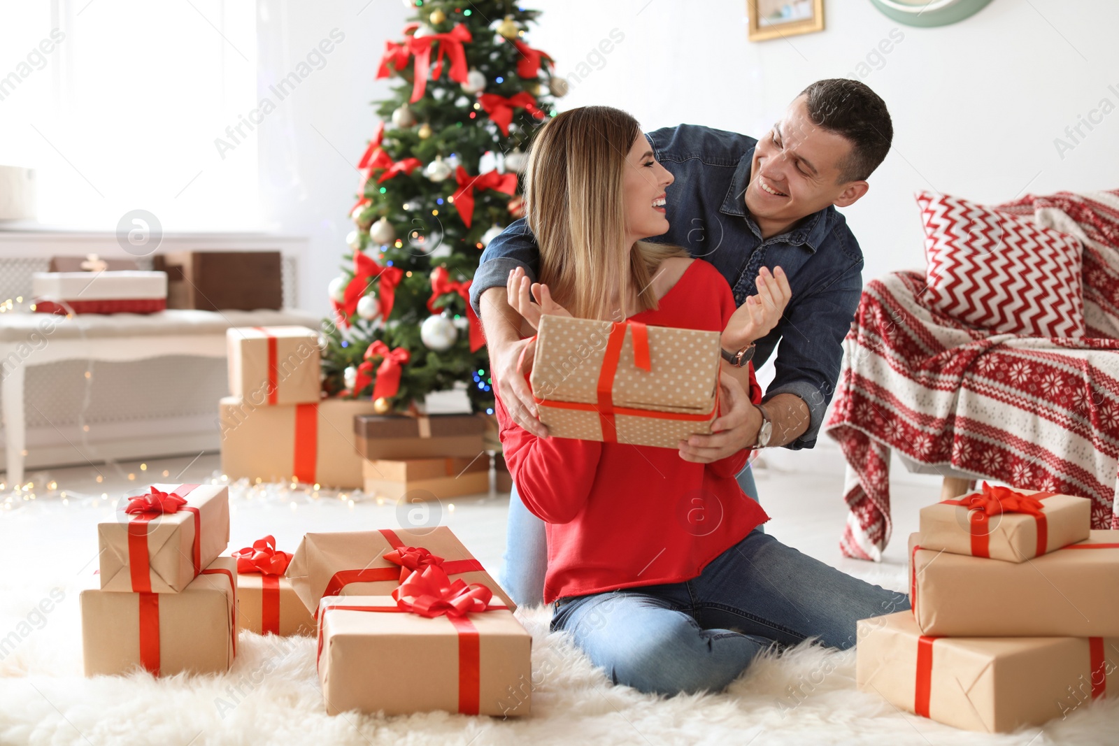 Photo of Young man surprising his girlfriend with Christmas gift at home