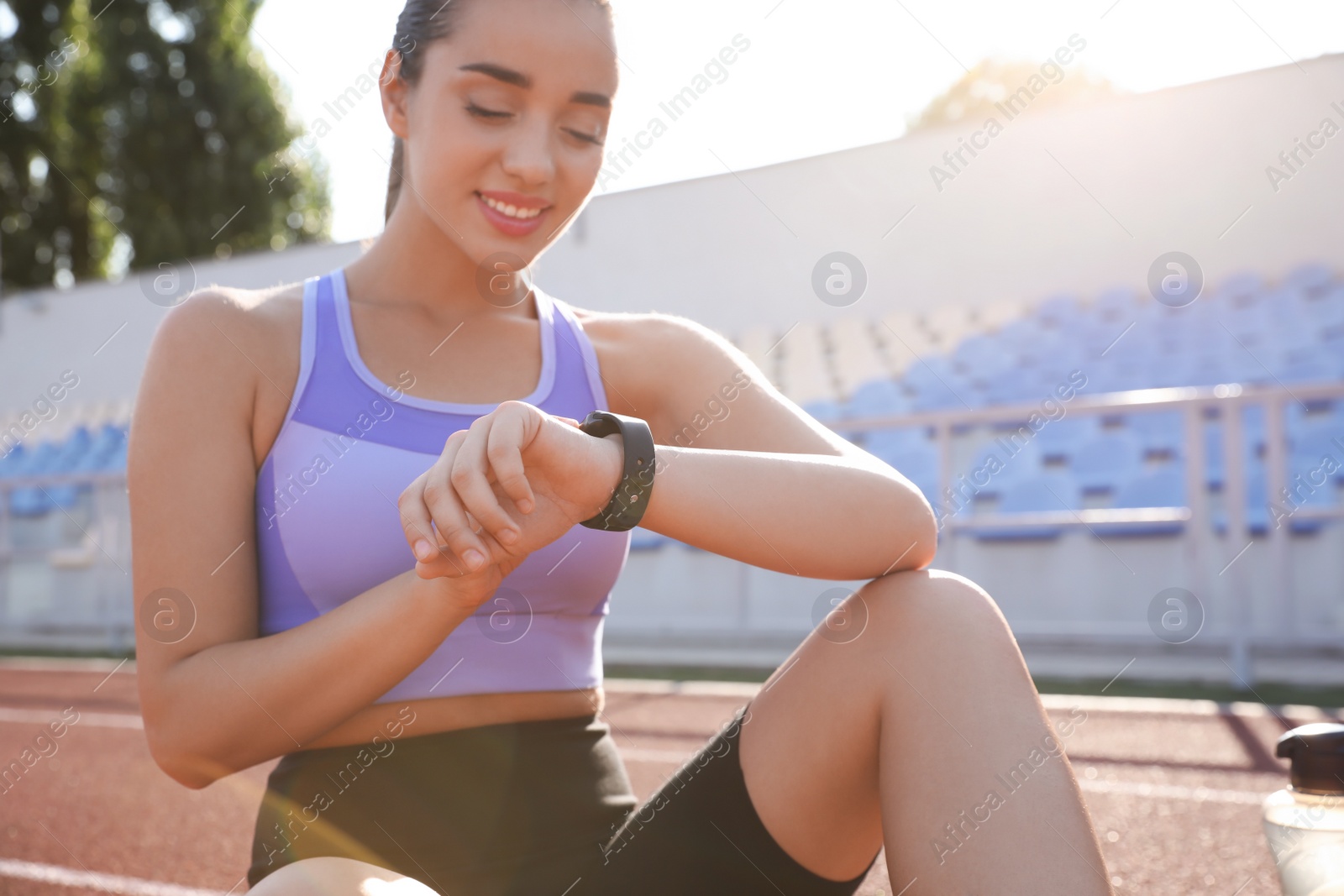 Photo of Woman checking fitness tracker after training at stadium