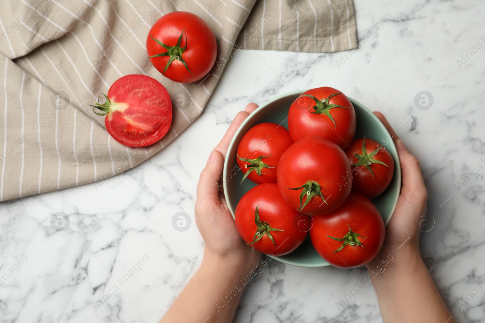 Photo of Woman with ripe tomatoes at white marble table, top view