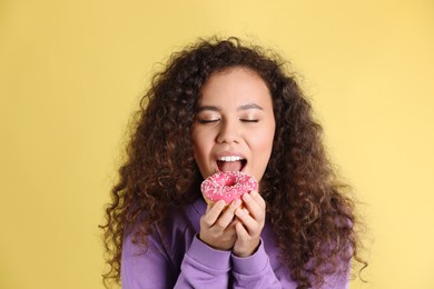 Photo of Beautiful African-American woman with donut on yellow background