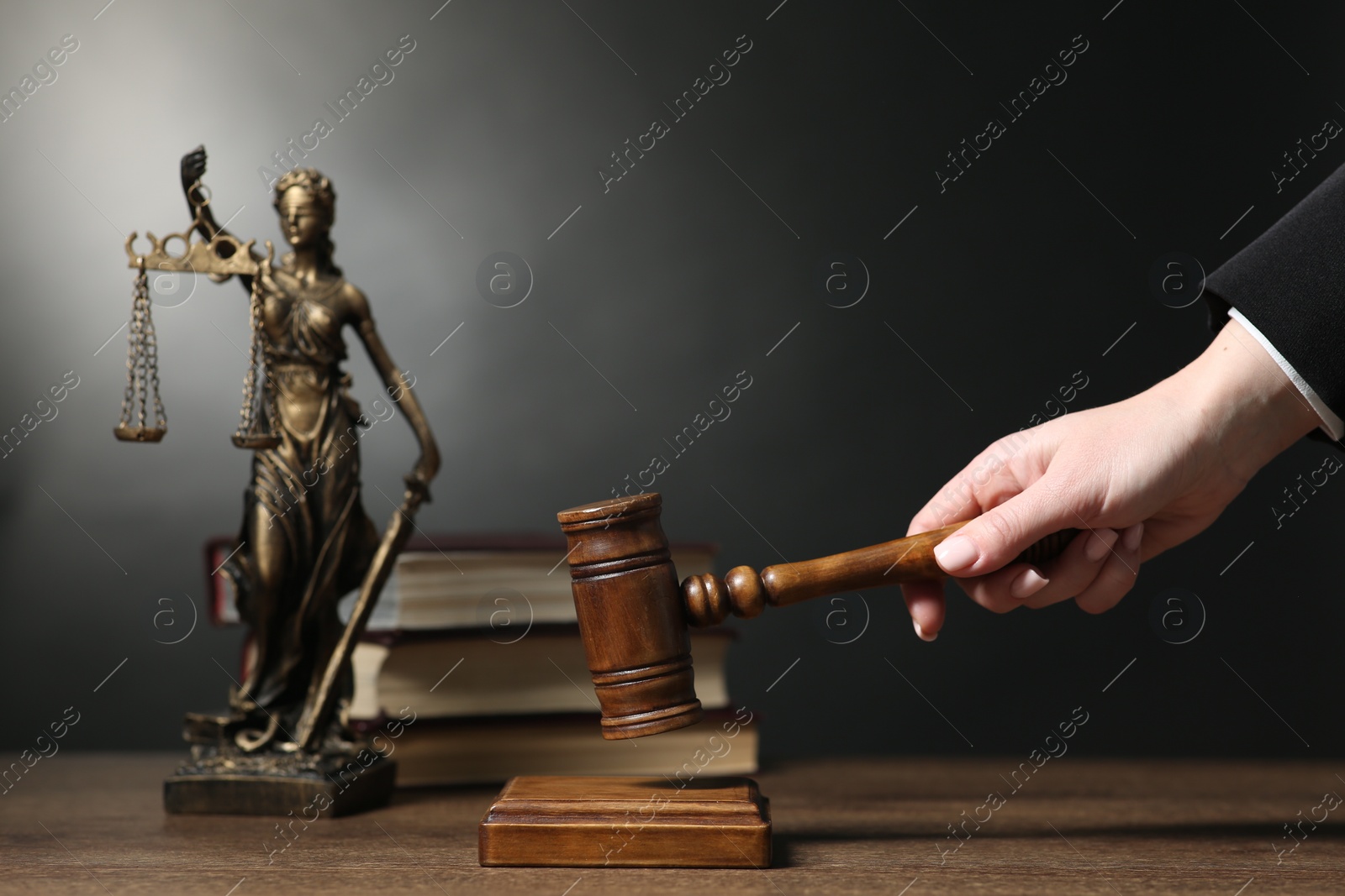 Photo of Judge striking mallet at wooden table against dark background, closeup. Space for text