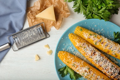 Photo of Flat lay composition of grilled corn cobs with grated cheese on white wooden table
