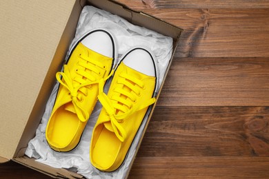 Photo of Pair of stylish sport shoes in cardboard box on wooden background, top view. Space for text