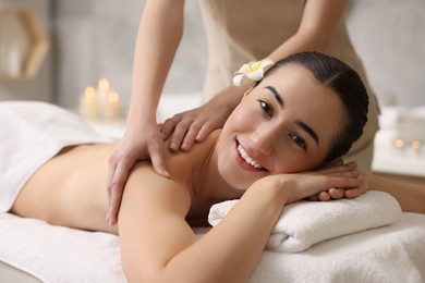 Woman receiving back massage on couch in spa salon