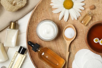 Photo of Flat lay composition with chamomile and cosmetic products on white wooden table