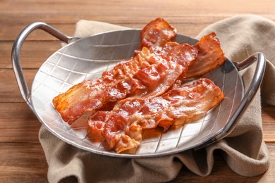 Dish with fried bacon on wooden background