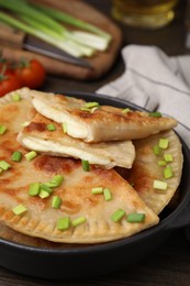Photo of Delicious fried chebureki with cheese and green onion on wooden table, closeup