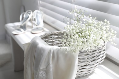 Photo of Basket with beautiful flowers and wedding shoes on window sill indoors
