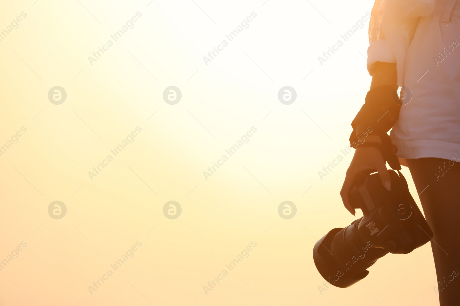 Photo of Photographer with professional camera outdoors at sunset, closeup