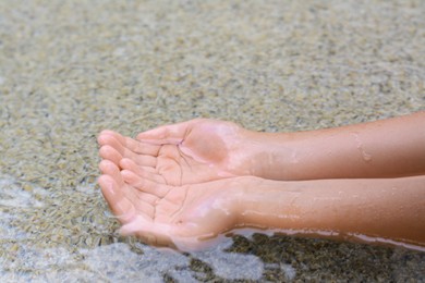 Kid dipping hands in water outdoors, closeup