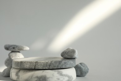 Photo of Presentation for product. Stone podium and pebbles on light grey background. Space for text