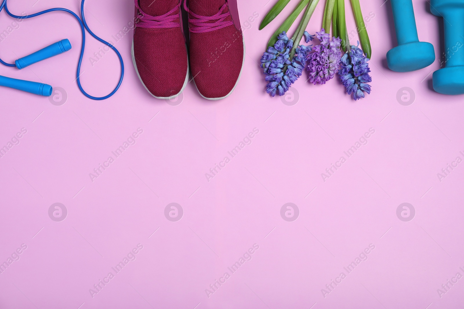 Photo of Flat lay composition with spring flowers and sports items on pink background. Space for text