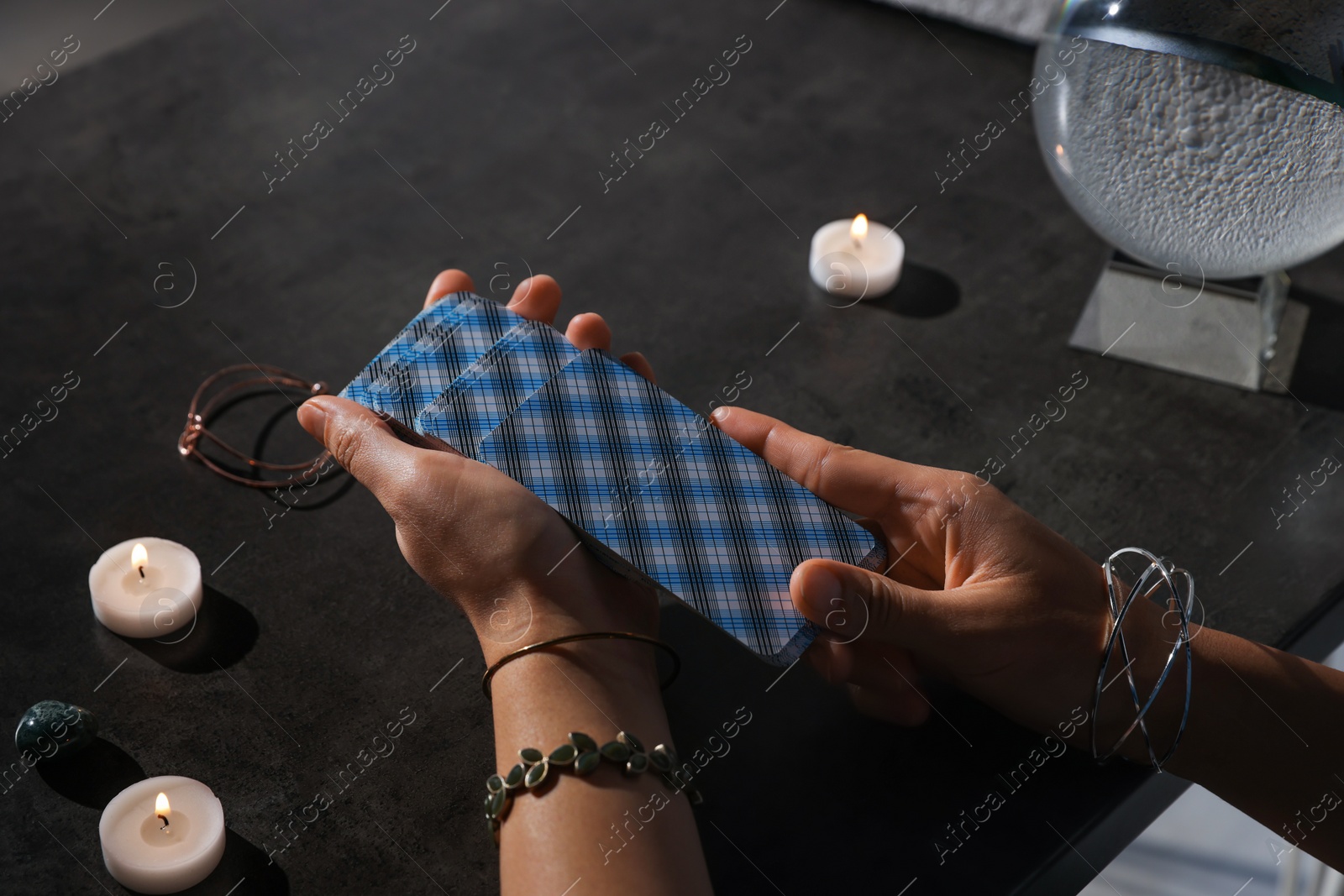 Photo of Fortune teller with deck of tarot cards at grey table, closeup