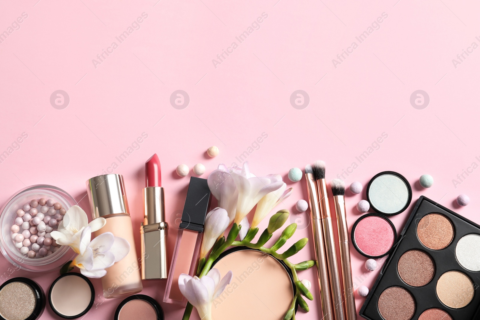 Photo of Different makeup products with flowers on color background. Space for text